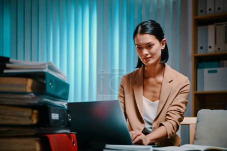 Photo for Young businesswoman working on laptop in office late at night - Royalty Free Image