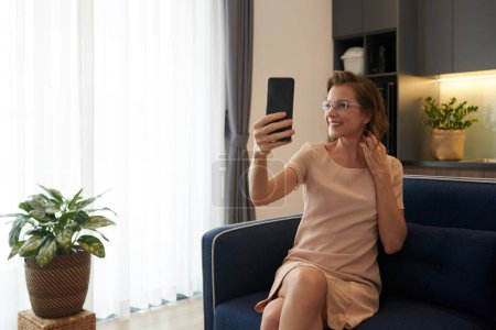 Téléchargez les photos : Portrait de femme d'âge moyen souriante en lunettes prenant selfie pour les médias sociaux - en image libre de droit