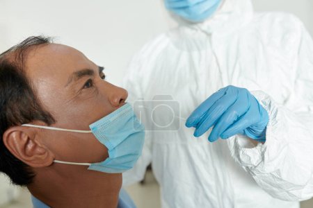 Foto de Enfermera tomando hisopo nasal del paciente mayor para detectar una posible infección por coronavirus - Imagen libre de derechos