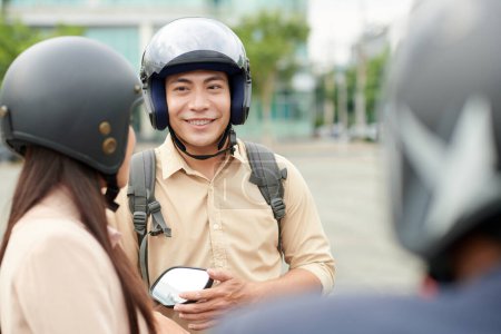 Photo for Cheerful young man wearing protective helmet when talking to friends - Royalty Free Image