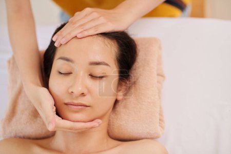 Foto de Imagen de cerca de una mujer joven recibiendo masaje facial en el salón de spa, vista desde arriba - Imagen libre de derechos