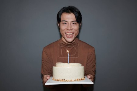 Téléchargez les photos : Portrait d'homme heureux tenant gâteau d'anniversaire avec une bougie - en image libre de droit