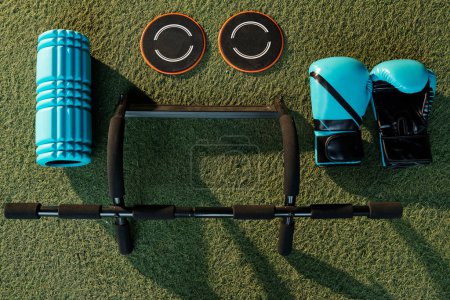 Photo for Gym equipment like pull-up baron, boxing gloves, myofascial release roller and core sliders on artificial gym turf - Royalty Free Image