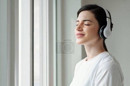 Photo for Young woman enjoying sunlight and listening to affirmations in the morning - Royalty Free Image