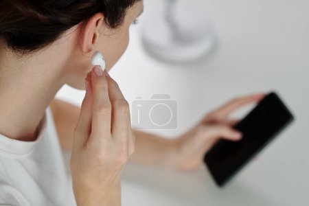 Foto de Mujer insertando auriculares para escuchar el mensaje de voz de su compañero de trabajo - Imagen libre de derechos