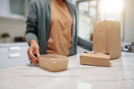Photo for Woman taking containers with dishes out of paper package - Royalty Free Image