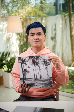 Téléchargez les photos : Portrait d'un jeune homme fier montrant une photographie en noir et blanc qu'il a faite - en image libre de droit