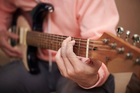 Téléchargez les photos : Image rapprochée d'un jeune homme jouant de la guitare électrique - en image libre de droit
