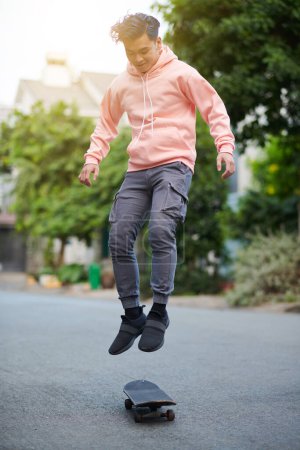 Photo for Active young man performing stunt, jumping on skateboard - Royalty Free Image