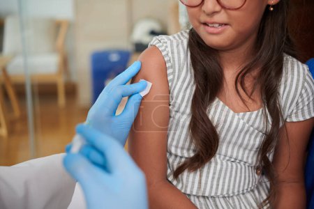 Photo for Closeup image of doctor wiping injection site on arm of patient with cotton pad - Royalty Free Image