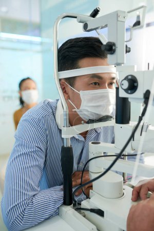 Photo for Asian man getting tested for glaucoma with modern equipment in office of optometrist - Royalty Free Image