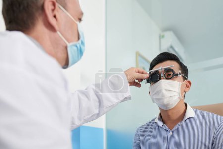 Photo for Ophthalmologist covering one eye of patient in adjustable optical trial lens frame with special plastic plate - Royalty Free Image