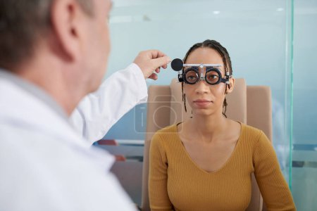 Photo for Ophthalmologist helping female patient with putting on trial frames - Royalty Free Image