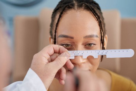 Foto de Oftalmólogo midiendo distancia entre ojos de paciente femenina con regla especial - Imagen libre de derechos