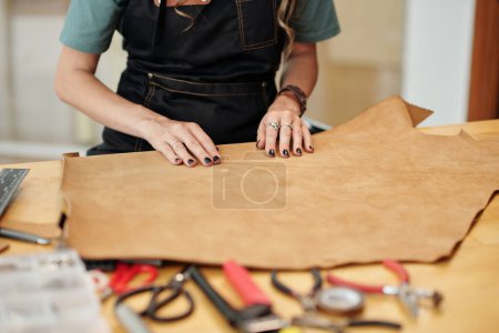 Téléchargez les photos : Jeune femme créative travaillant avec le cuir dans son atelier - en image libre de droit