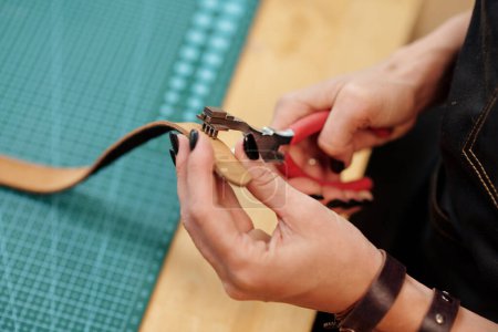 Téléchargez les photos : Mains de l'artisan utilisant l'outil pour faire des trous dans la ceinture - en image libre de droit