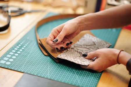 Photo for Hands of leather worker sewing parts of leather bag together - Royalty Free Image