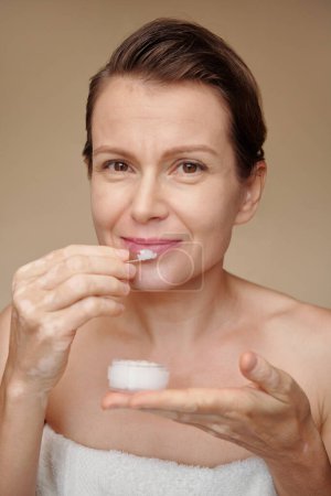 Téléchargez les photos : Sourire femme mûre appliquant gommage de sucre sur les lèvres - en image libre de droit