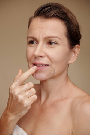 Foto de Retrato de mujer madura aplicando bálsamo nutritivo en los labios - Imagen libre de derechos