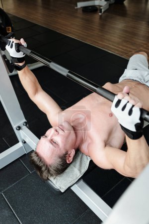 Téléchargez les photos : Homme fort faisant l'exercice de presse de banc dans la salle de gym - en image libre de droit