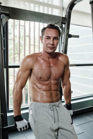 Foto de Retrato de hombre musculoso en forma sin camisa apoyado en la barra y mirando a la cámara - Imagen libre de derechos