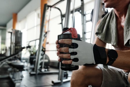 Photo for Cropped image of sportsman holding shaker with protein cocktail when resting between reps - Royalty Free Image