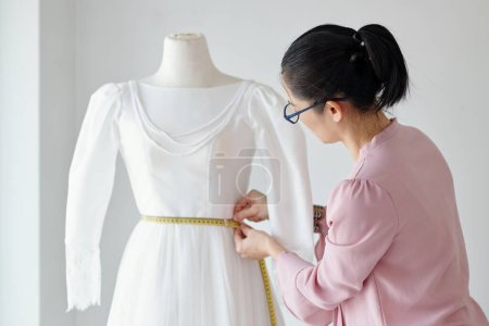 Foto de Medición de la cintura del maniquí a medida cuando se trabaja en el vestido para el cliente - Imagen libre de derechos