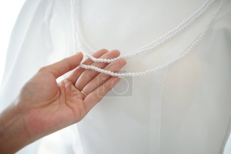 Photo for Woman touching peral necklace on mannequin with wedding dress - Royalty Free Image