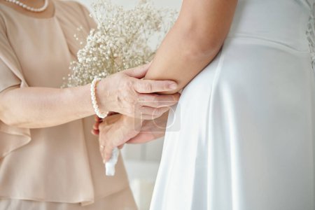 Téléchargez les photos : Mère touchant la main de la mariée pour la soutenir le jour du mariage - en image libre de droit