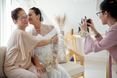 Braut küsst ihre Wangenmutter, wenn sie sie für die sozialen Medien fotografiert