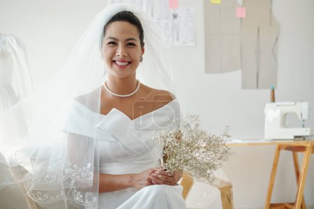 Foto de Retrato de la feliz novia sonriente en vestido de novia sosteniendo flores - Imagen libre de derechos