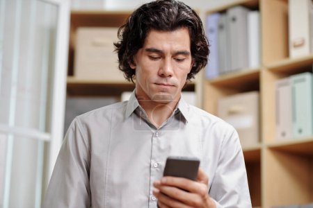 Téléchargez les photos : Homme d'affaires malheureux lisant un message texte avec de mauvaises nouvelles sur smartphone - en image libre de droit