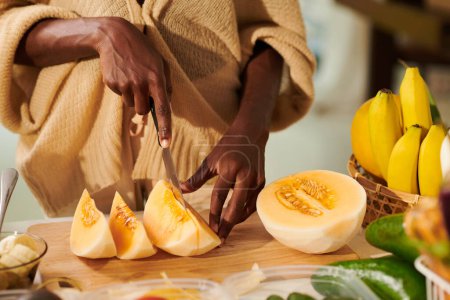 Téléchargez les photos : Image rapprochée de la femme coupant le melon en tranches pour servir de dessert - en image libre de droit