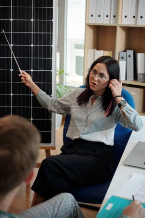 Photo for Manager pointing at solar panel when explaining principle of work to customer or new worker - Royalty Free Image