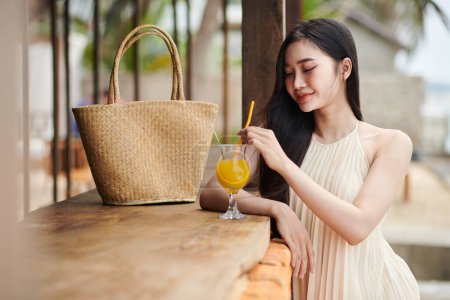 Photo for Young woman drinking fruit cocktail at bar on beach - Royalty Free Image