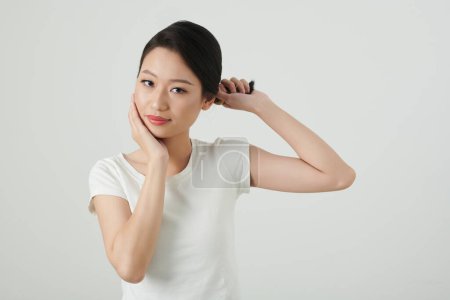 Photo for Portrait of young Asian woman twisting hair and touching her face - Royalty Free Image
