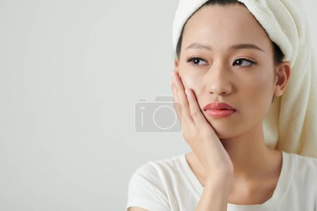 Photo for Young woman suffering from toothache, she is touching cheek and looking away - Royalty Free Image