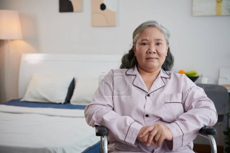Foto de Retrato de mujer asiática triste enferma sentada en silla de ruedas en el dormitorio del hospital - Imagen libre de derechos