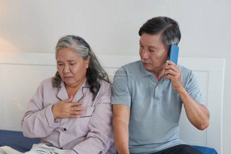 Foto de Hombre mayor preocupado llamando al médico para decirle que su esposa sufría de fuertes dolores de corazón - Imagen libre de derechos