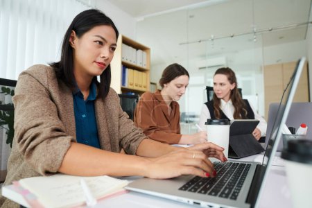 Téléchargez les photos : Femme d'affaires répondant aux e-mails lorsque son collègue discute du document en arrière-plan - en image libre de droit