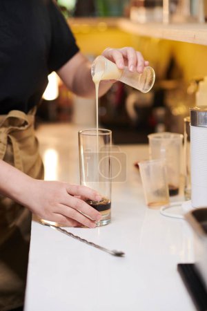 Téléchargez les photos : Barista ajoutant du lait condensé dans un grand verre avec expresso - en image libre de droit