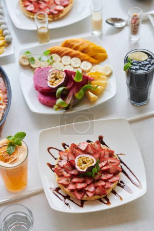 Téléchargez les photos : Tartelette aux fraises sucrée et fruits coupés sur une table de café - en image libre de droit