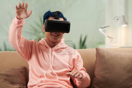 Téléchargez les photos : Jeune homme heureux dans casque jouant jeu de réalité virtuelle - en image libre de droit