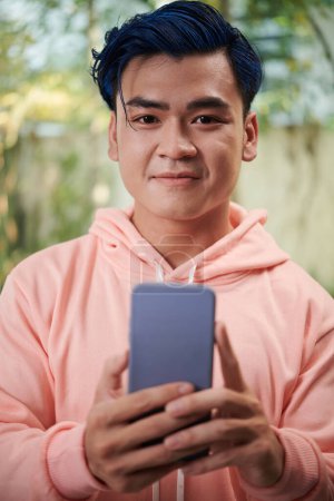 Téléchargez les photos : Portrait de jeune homme joyeux aux cheveux bleus prenant selfie - en image libre de droit