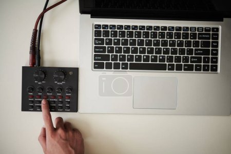 Téléchargez les photos : Amplificateur de réglage du musicien lorsque vous vous préparez à enregistrer la mélodie sur un ordinateur portable - en image libre de droit
