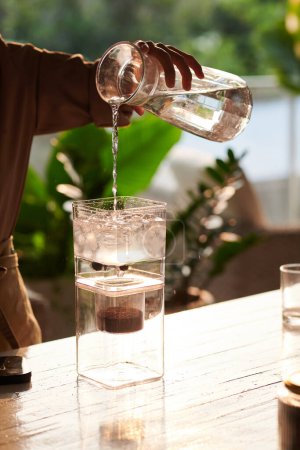 Téléchargez les photos : Barista verser de l'eau fraîche dans une cafetière froide - en image libre de droit