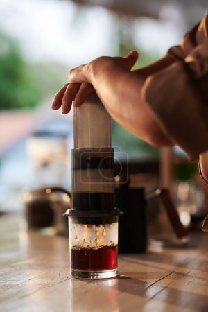 Téléchargez les photos : Barista en utilisant aéropress lors de la fabrication d'une tasse de café pour le client - en image libre de droit