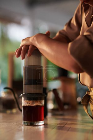 Closeup image of coffeeshop barista using aeropress when making coffee cup