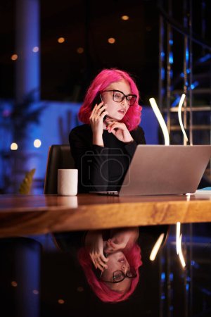 Foto de Joven empresaria trabajando hasta tarde por la noche, tomando café y hablando por teléfono - Imagen libre de derechos