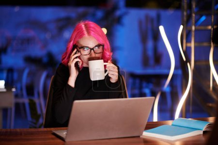 Téléchargez les photos : Femme d'affaires répondant à un appel téléphonique tardif d'un autre pays et buvant du café - en image libre de droit